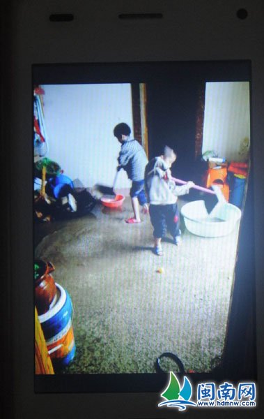 张女士的孩子们在清理被水浸过的租房（张女士用手机